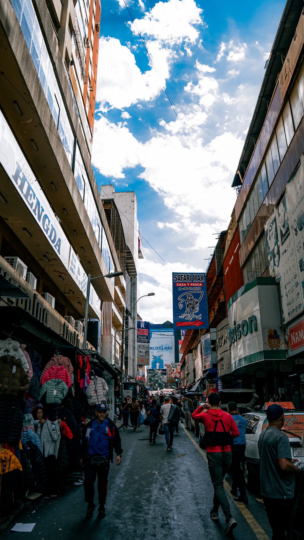 Calle comercial de Ciudad del Este con locales, cartelería y gente caminando entre los negocios