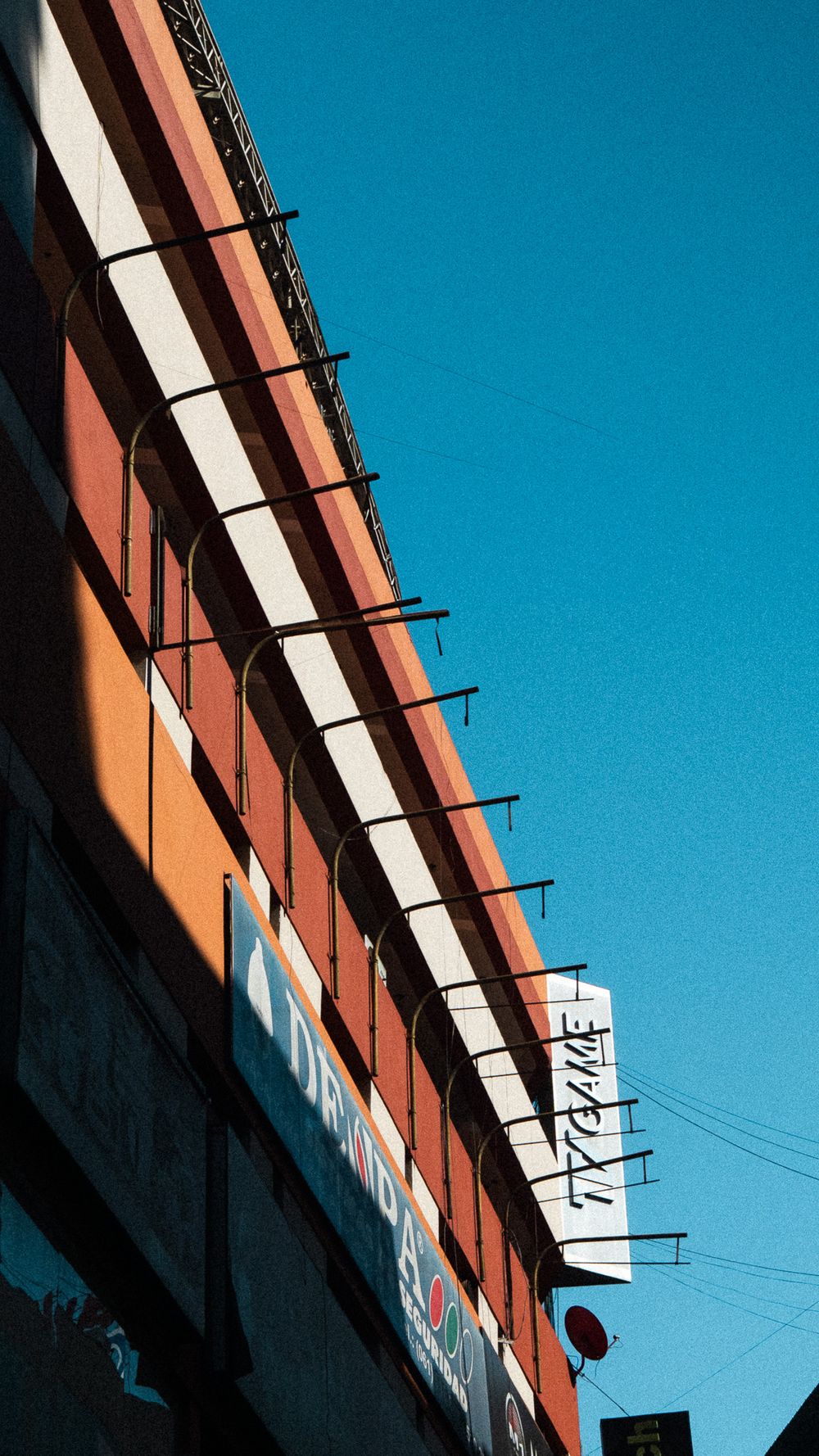 Fachada de un local comercial con franjas diagonales de colores y un cartel de neón, en Ciudad del Este