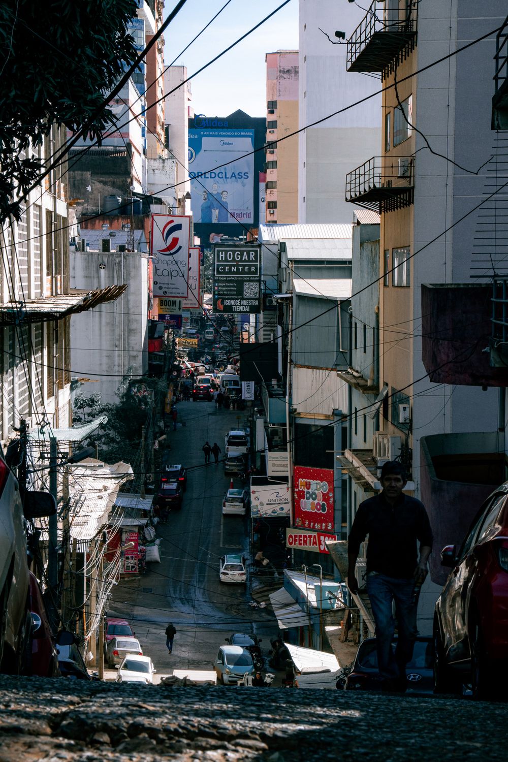 Vista de una calle en pendiente de Ciudad del Este llena de carteles comerciales y tránsito