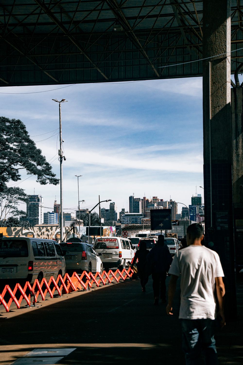 Vista desde una terminal cubierta hacia una avenida de Ciudad del Este con vallas de tránsito y el skyline al fondo